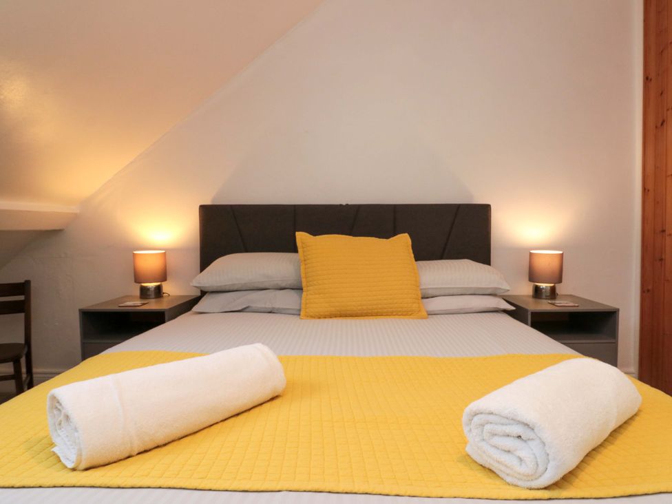 A bedroom with a bed and bedside lamps at Saints Cottage in Scarborough