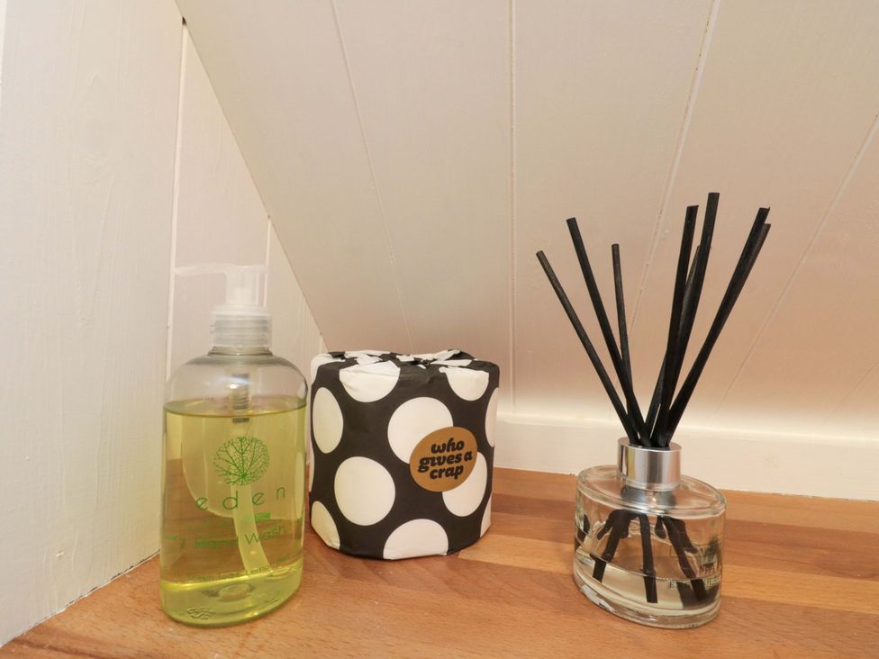 Hand wash, toilet paper, and reed diffuser in a bathroom at Saints Cottage in Scarborough