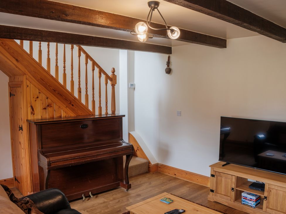 A living room with a piano and television at Shires Rest in Hartington