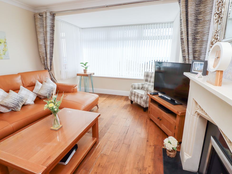 A living room with a sofa and a television at Beach Cove View in Newbiggin-by-the-Sea