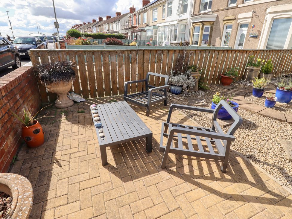 A garden area with chairs and a table at Beach Cove View in Newbiggin-by-the-Sea