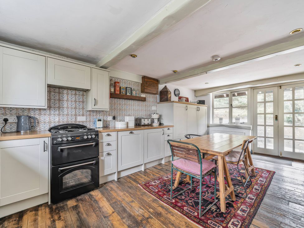 A kitchen with cabinets, stove, table, and chairs at Spring Park Farmhouse in Launceston