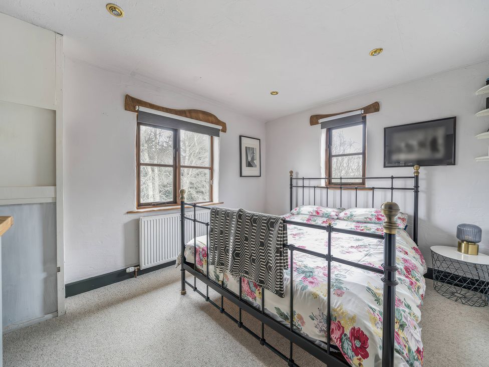 A bedroom with a bed and two windows at Spring Park Farmhouse in Launceston