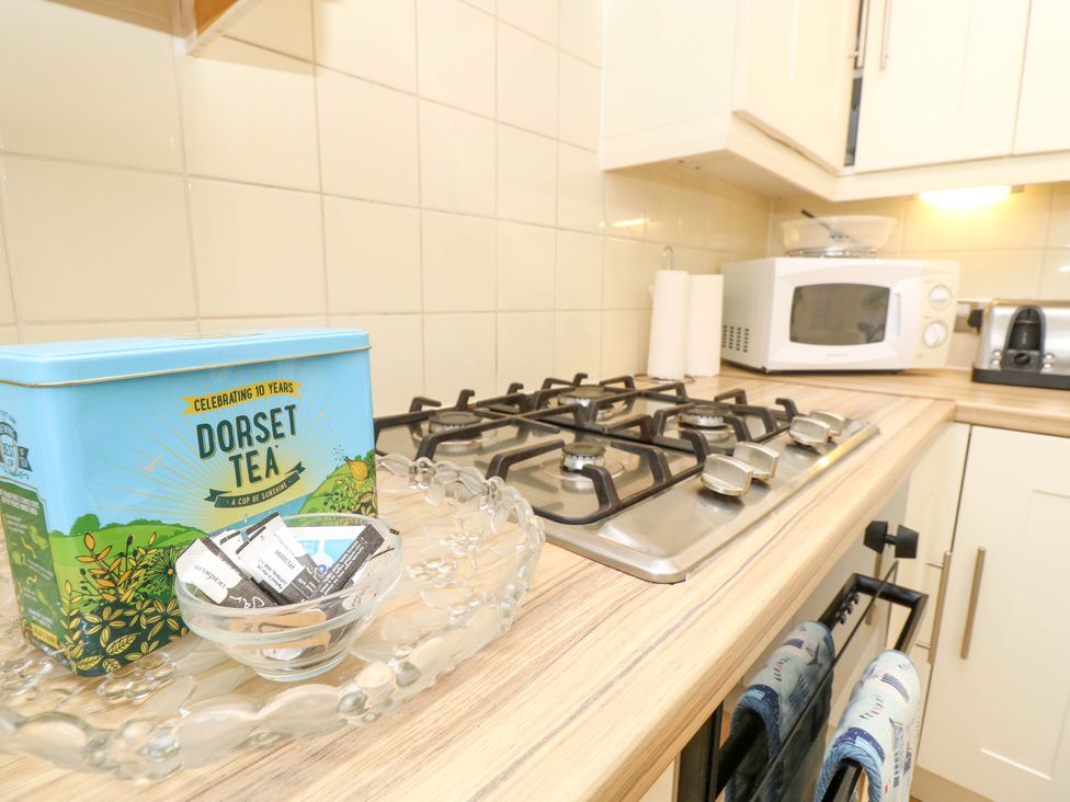 A kitchen with a stove, microwave, and tea tin at 32 Cranleigh Close Tuckton