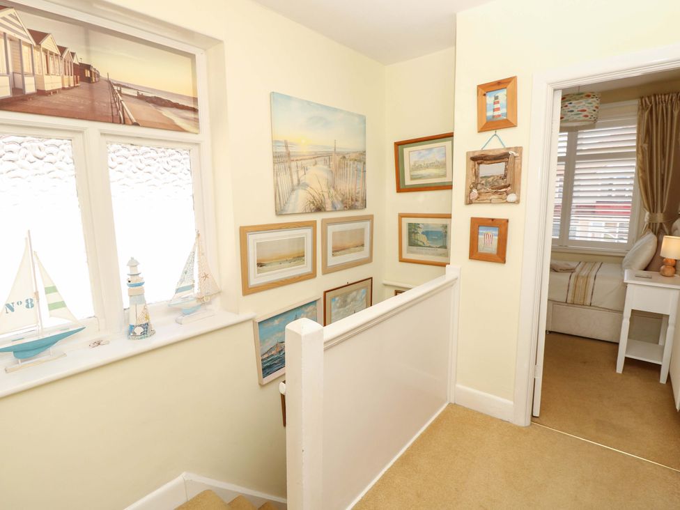 A hallway with framed pictures and a decorative sailboat at 32 Cranleigh Close Tuckton