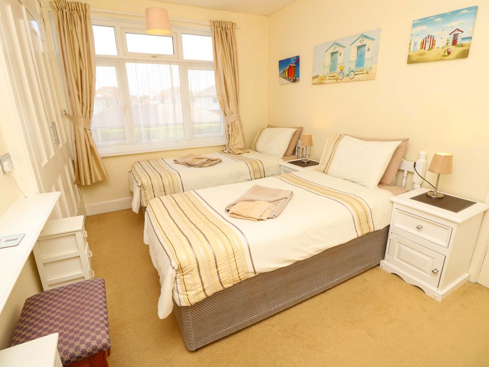 A bedroom with two beds and paintings on the wall at 32 Cranleigh Close Tuckton