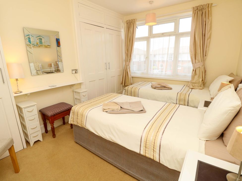 A bedroom with two beds and a mirror at 32 Cranleigh Close Tuckton