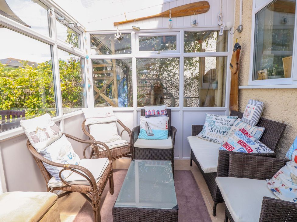 A conservatory with seating and a glass table at 32 Cranleigh Close Tuckton