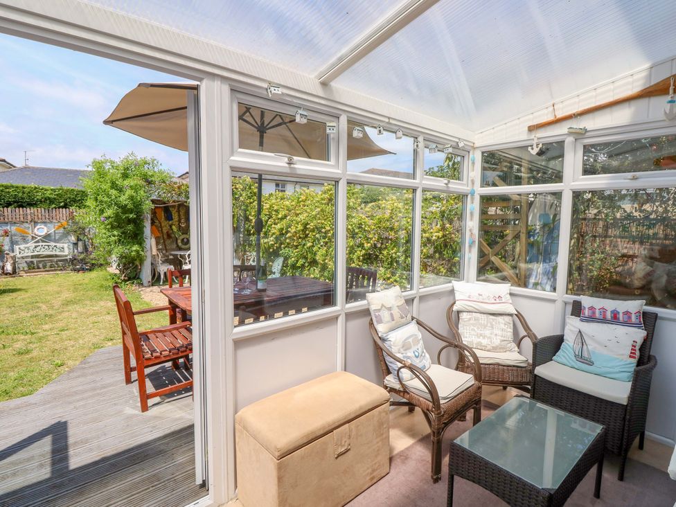A conservatory with seating and a table at 32 Cranleigh Close in Tuckton
