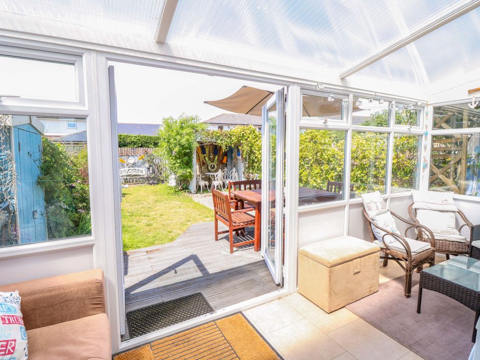 A conservatory leading to a garden with a table and chairs at 32 Cranleigh Close Tuckton