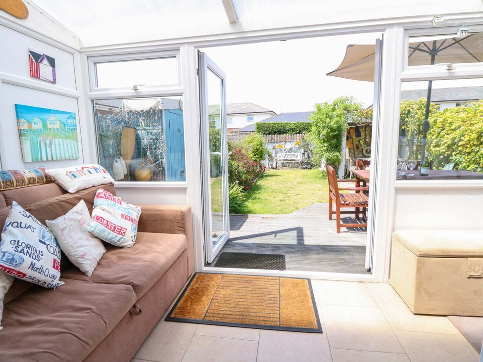 A conservatory with a sofa and access to a garden at 32 Cranleigh Close Tuckton