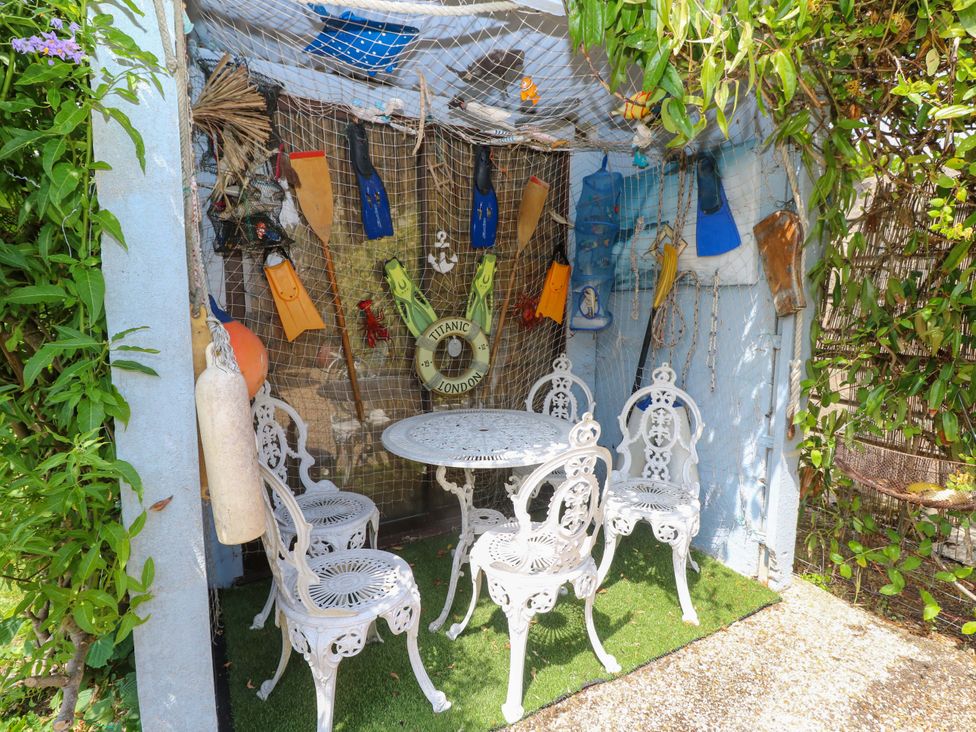 A seating area with white chairs and a table in a decorative outdoor area at 32 Cranleigh Close Tuckton