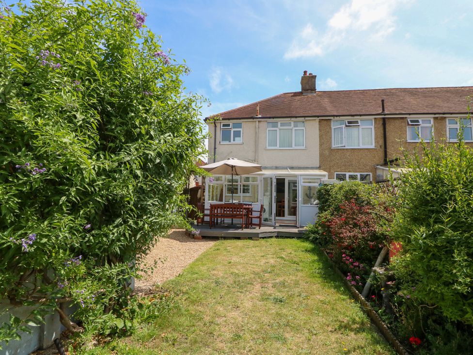 A garden with a house and decking at 32 Cranleigh Close Tuckton