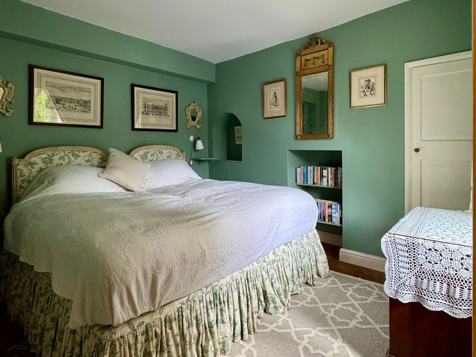 A bedroom with a bed and bookshelves at All Souls Cottage in Eastleach, Cotswolds