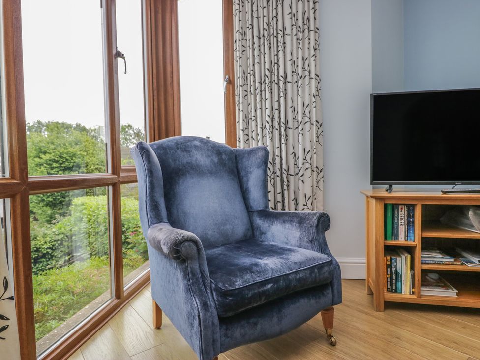 A living room with an armchair and television at Langtree in Arnside