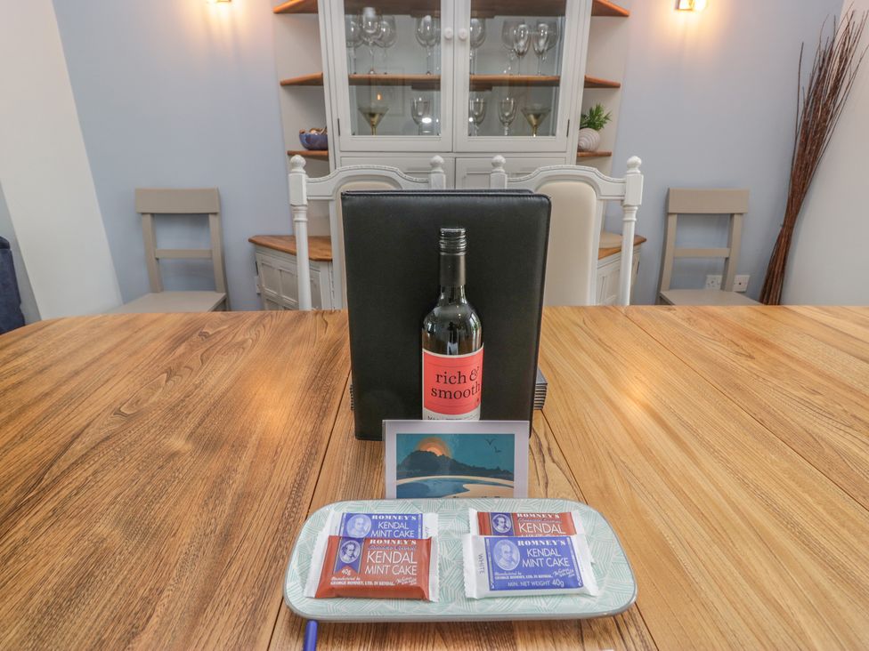 A dining room with wine, cake, and a menu at Langtree Arnside