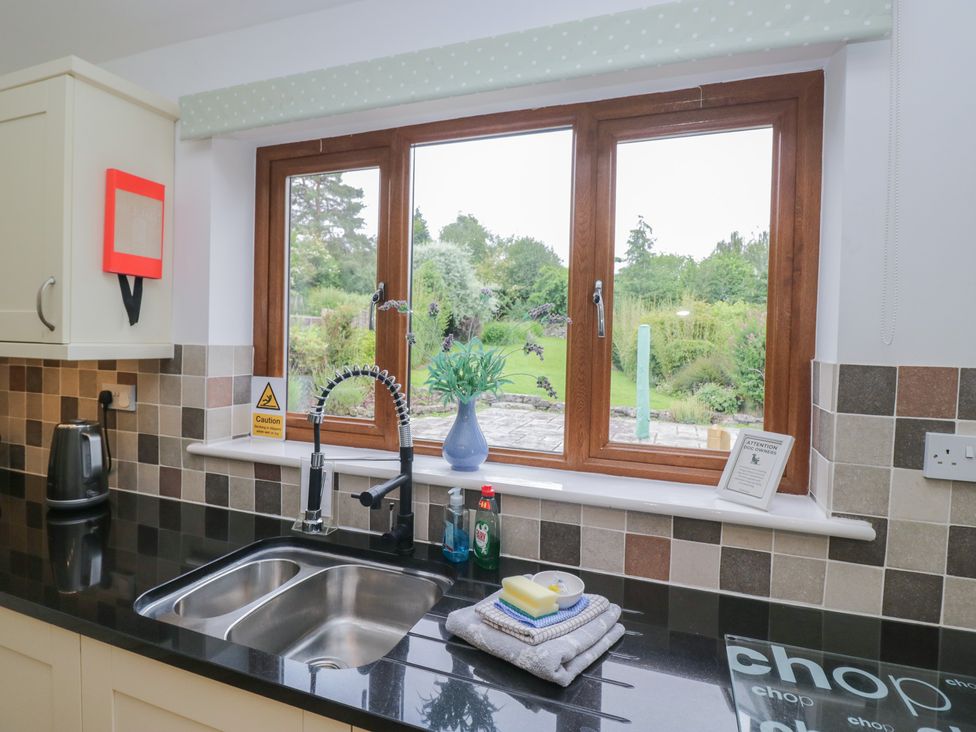 A kitchen with a sink and window overlooking the garden at Langtree in Arnside