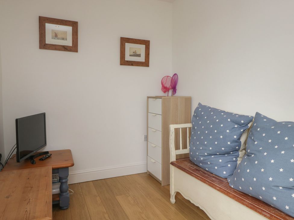 A living room with a television and sofa with cushions at Langtree in Arnside