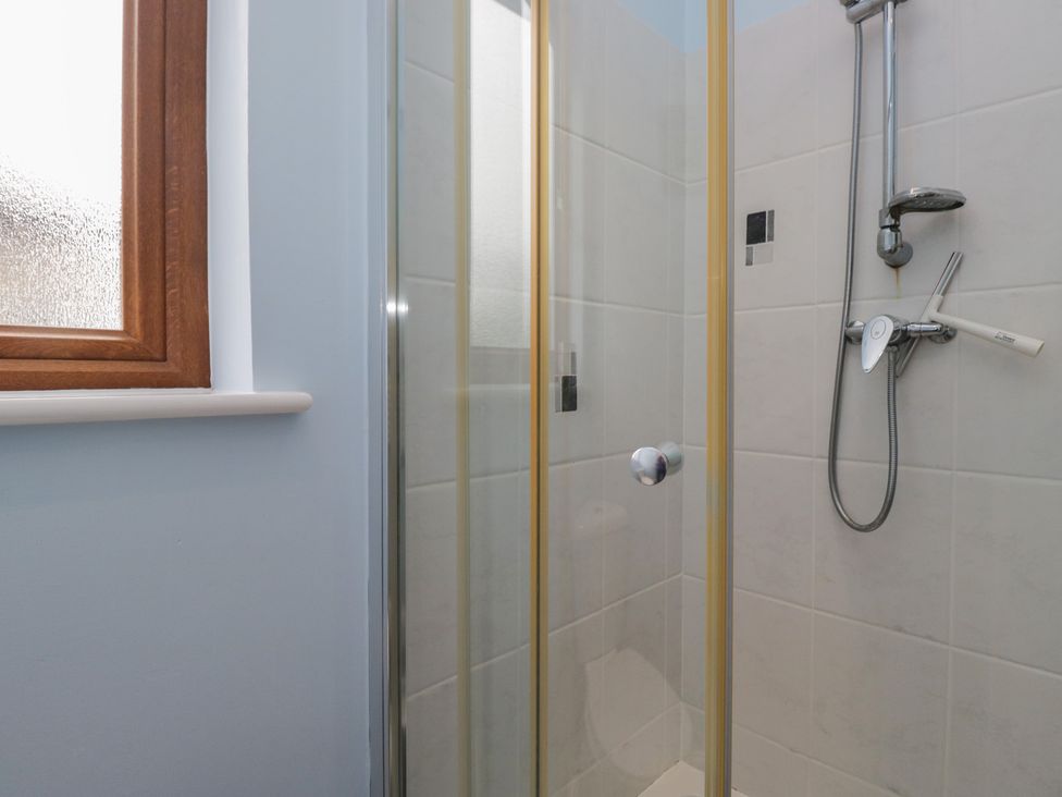 A shower area with a glass door and window at Langtree in Arnside