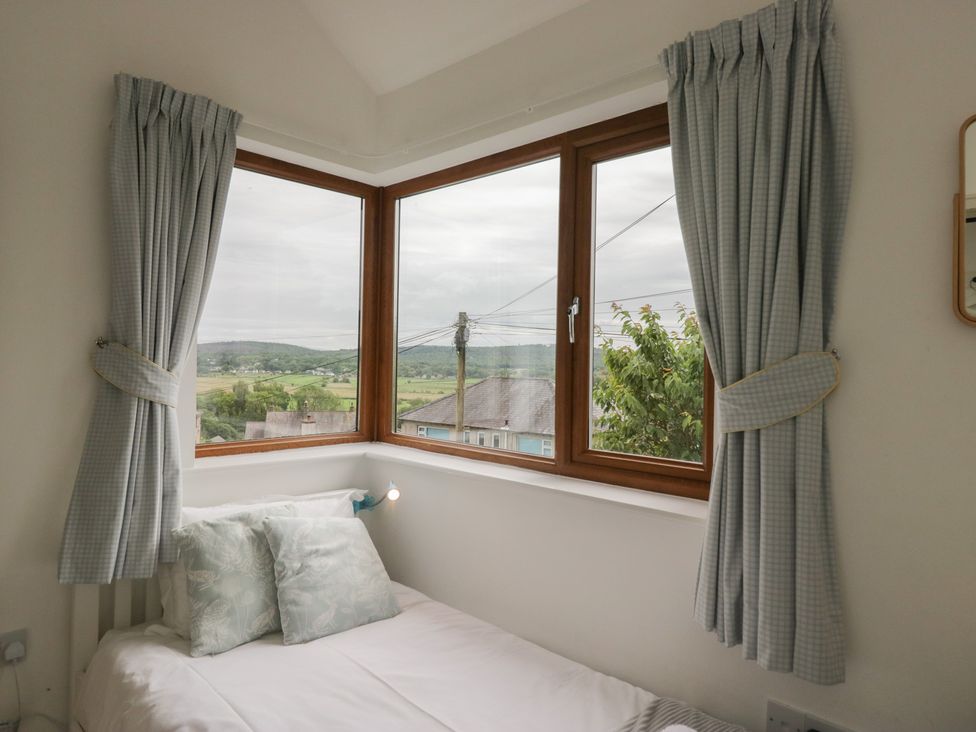 A bedroom with a bed and large windows at Langtree Arnside