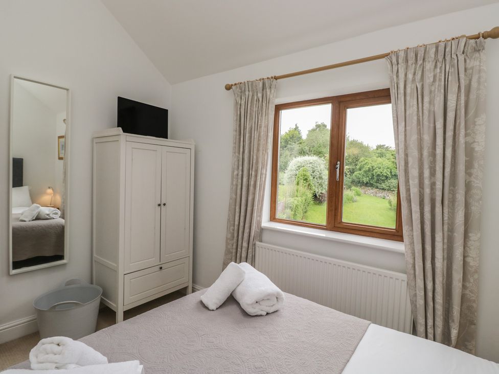 A bedroom with a bed and wardrobe at Langtree in Arnside