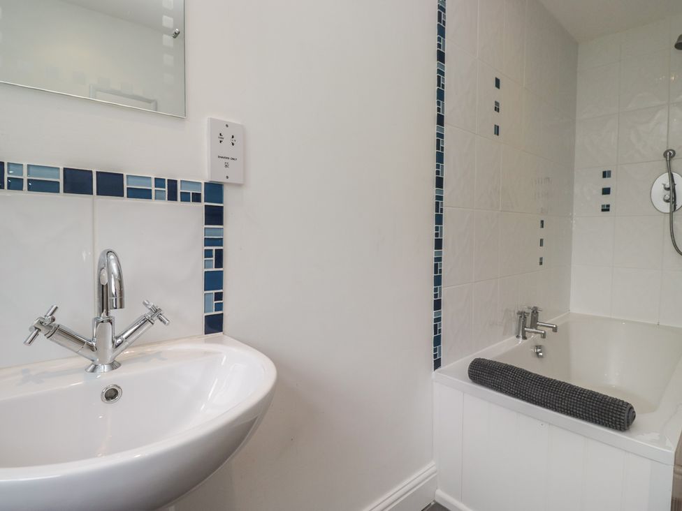 A bathroom featuring a washbasin and bathtub at Langtree in Arnside