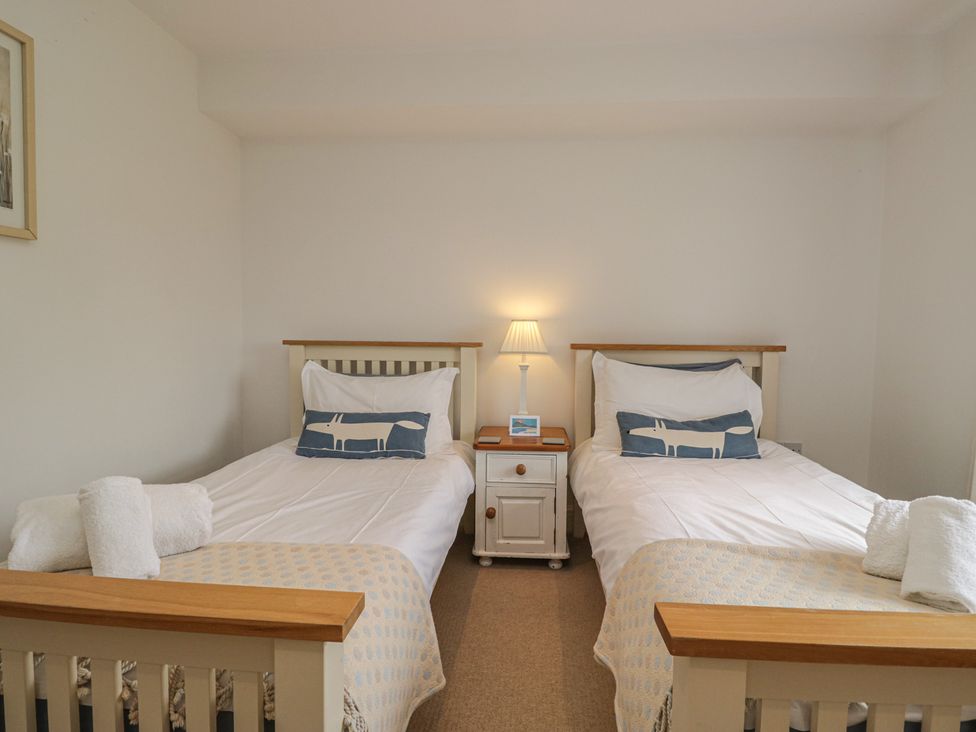 A bedroom with two beds and a bedside table with a lamp at Langtree in Arnside