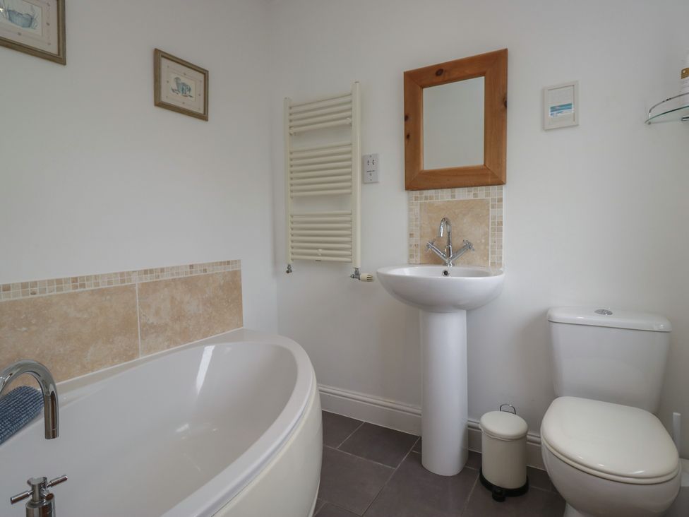 A bathroom with a bathtub, sink, and toilet at Langtree in Arnside