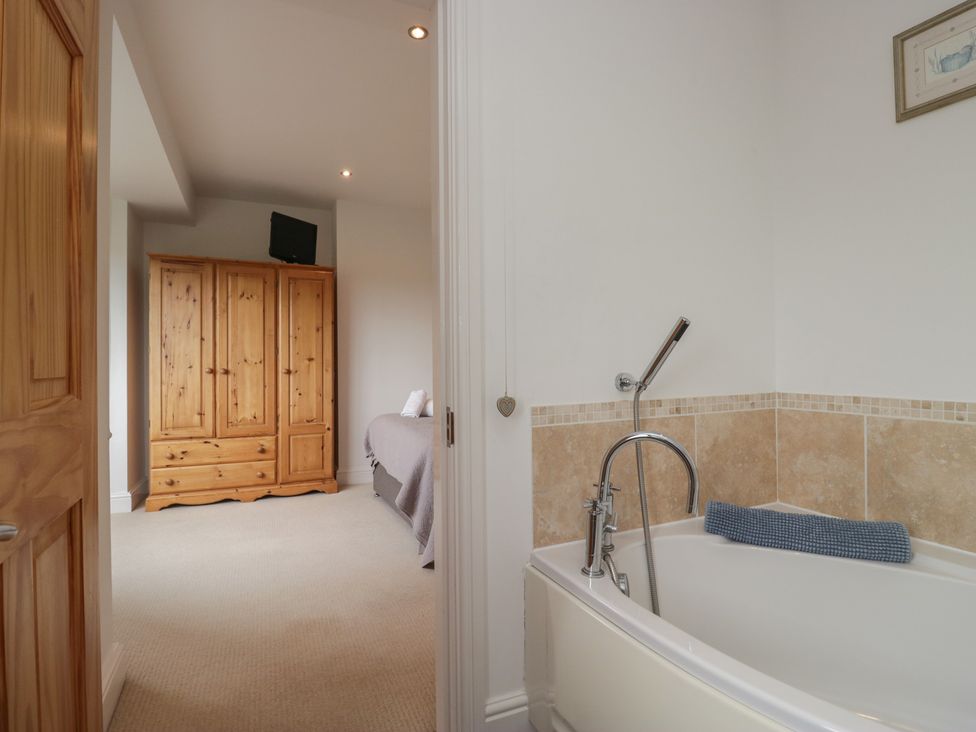 A bathroom with a bathtub and a wardrobe at Langtree in Arnside