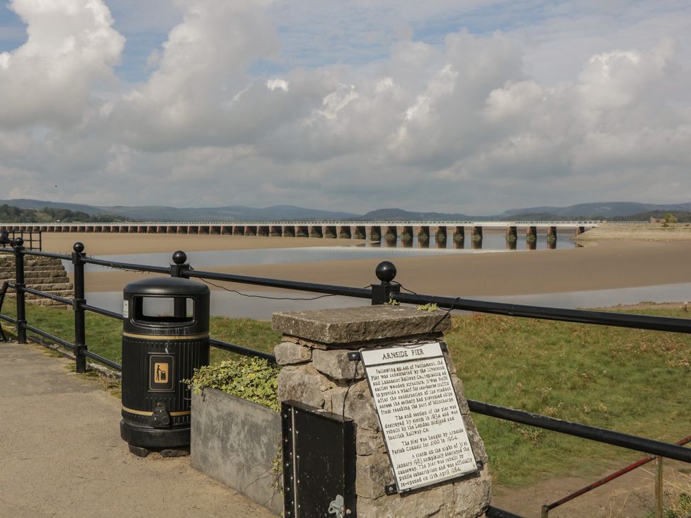A view of Arnside Pier with a trash can and information plaque in Arnside
