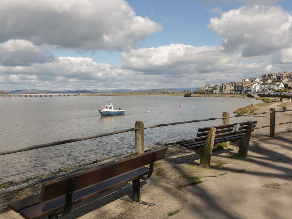 A view of a river with a boat and benches at Langtree Arnside