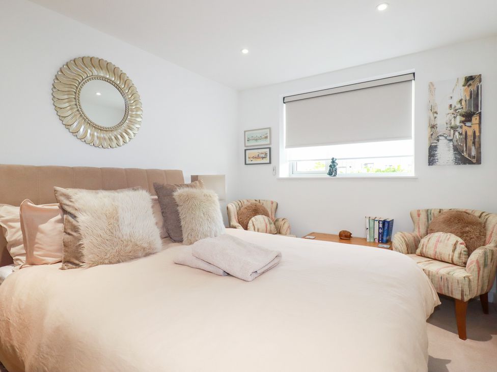 A bedroom with a bed and armchairs at Apartment no.21 in Newquay