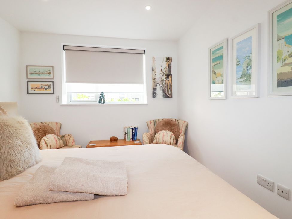 A bedroom with a bed and chairs at Apartment no.21 in Newquay