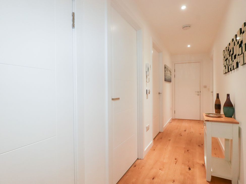 A hallway with doors and a table with vases at Apartment no.21 in Newquay