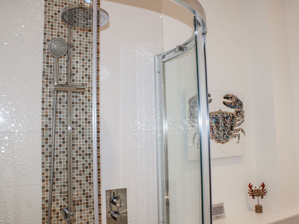 A shower with glass door and decorative crab art at 4 Ocean Reach in Bolberry