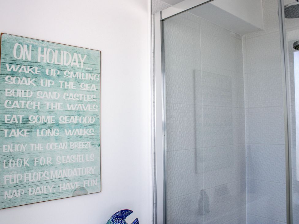 A bathroom with a shower and a decorative sign at 4 Ocean Reach in Bolberry