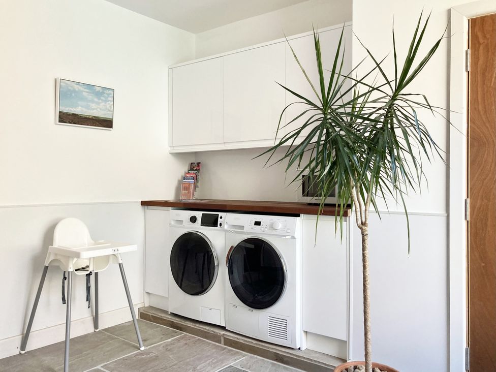 A laundry room with a washing machine and a tumble dryer at The Old Riverside School House in Hebden Bridge