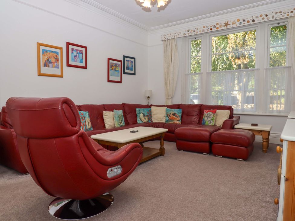 A living room with a red sofa and armchair at Babbacombe Hall in Babbacombe