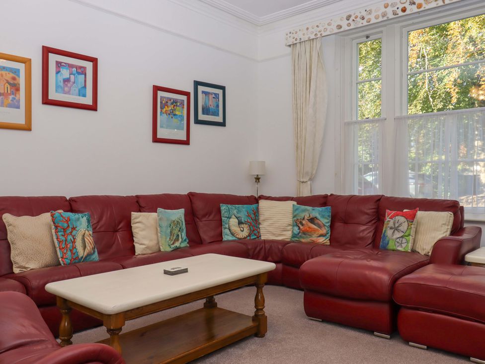 A living room with a red sofa and coffee table at Babbacombe Hall in Babbacombe