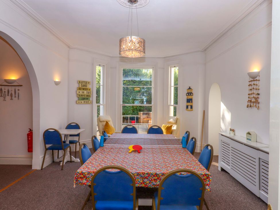 A dining room with a table and blue chairs at Babbacombe Hall in Babbacombe