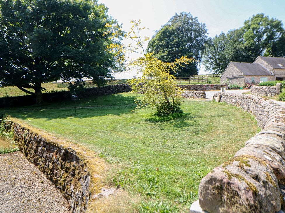 A garden with a tree and stone wall at Slade House Ilam, Staffordshire