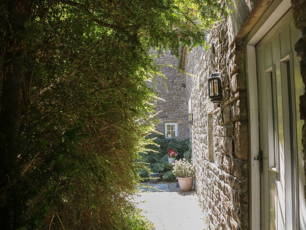 An outdoor path with stone walls and plants at Slade Cottage in Ilam