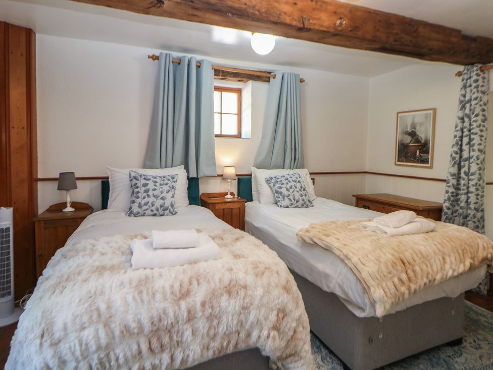 A bedroom with twin beds and wooden furniture at Slade Cottage in Ilam