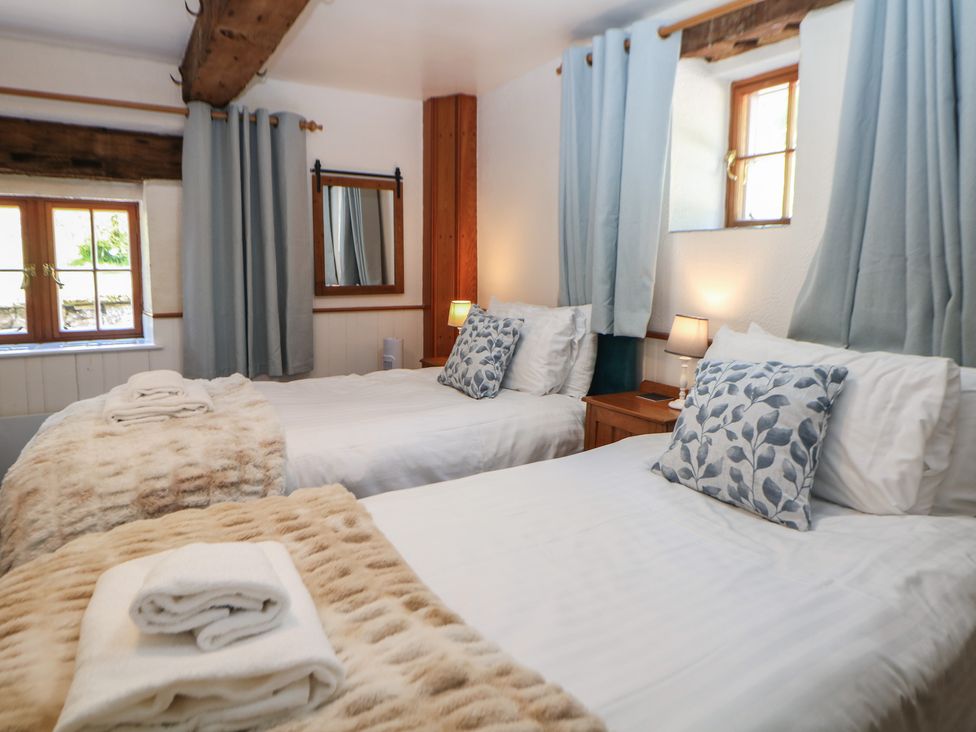 Two beds with pillows and towels in a bedroom at Slade Cottage Ilam