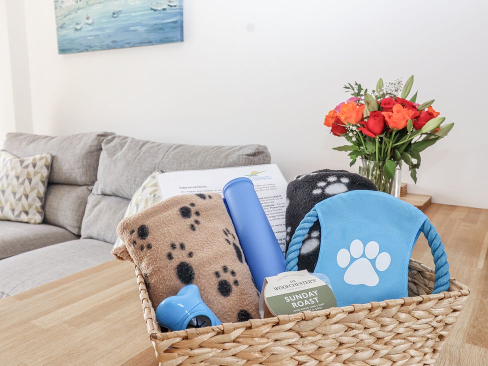 A basket with blankets and dog toys in a living room at Whitsand in Tideford