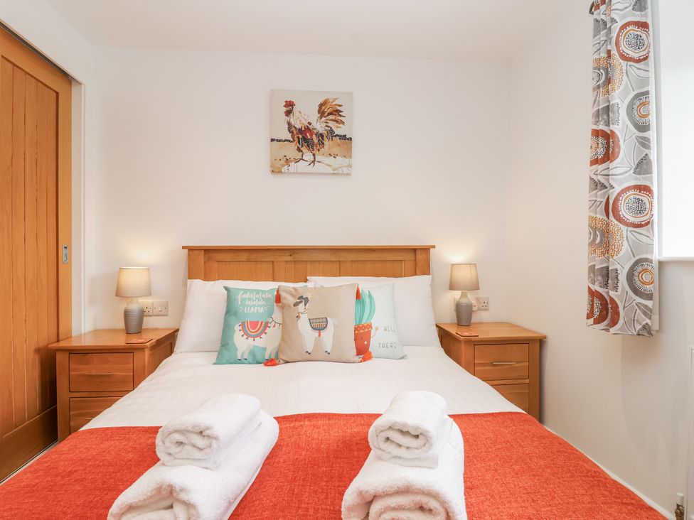 A bedroom with a bed and nightstands at Whitsand in Tideford