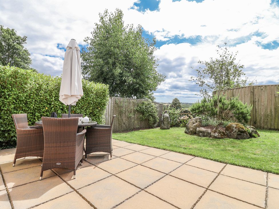 A garden with a table and chairs under an umbrella at Whitsand in Tideford