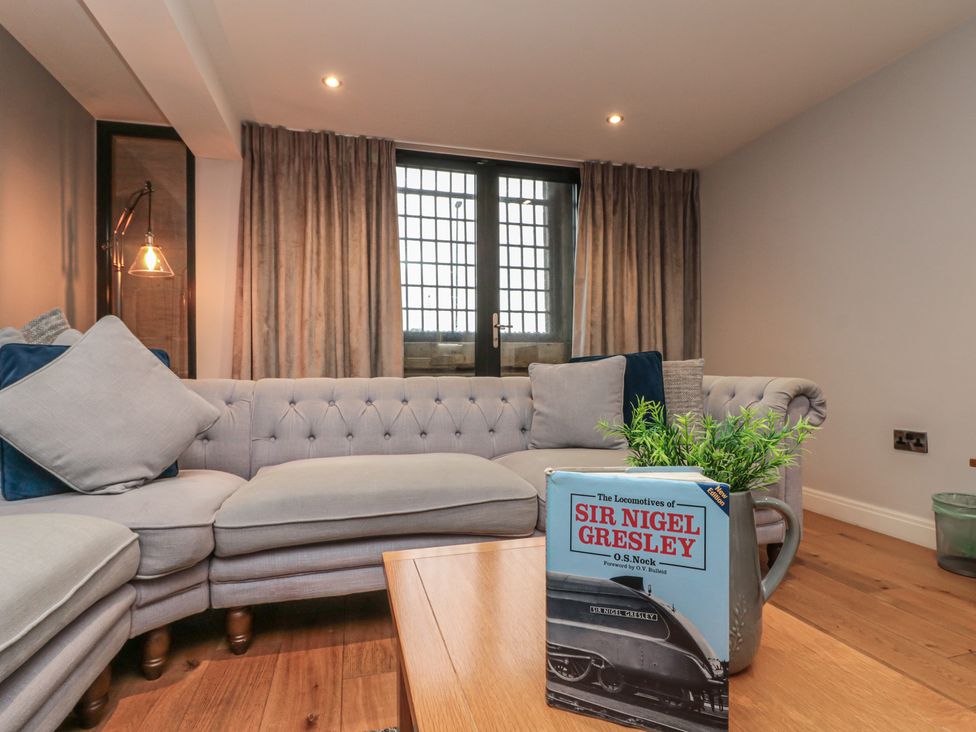 A living room with a sofa and a book on the table at Sir Nigel Gresley @ Engine Shed in Whitby