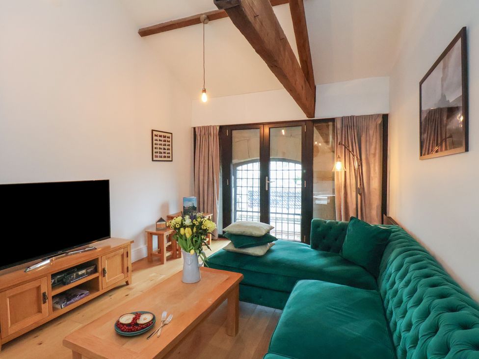 A living room with a green sofa and television at Repton @ Engine Shed in Whitby