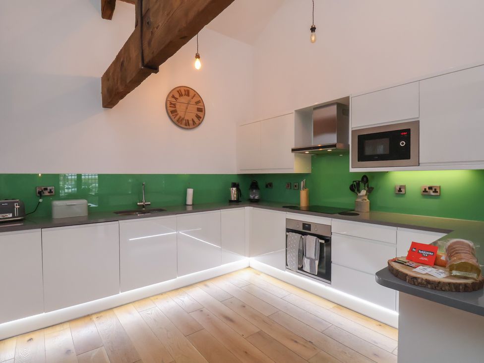 A kitchen with modern appliances and a green backsplash at Repton @ Engine Shed Whitby